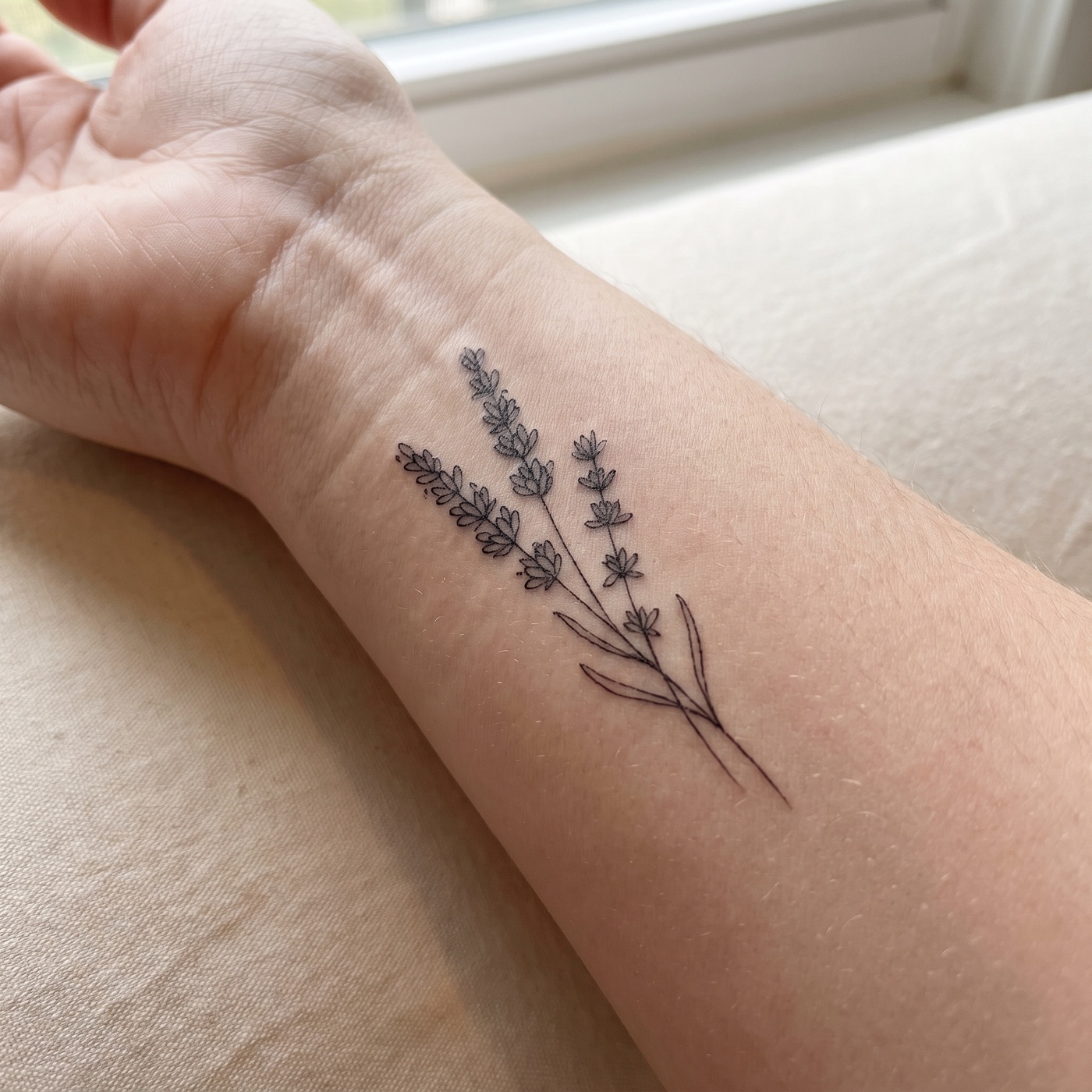 Small fine-line herb sprig tattoo on an inner wrist